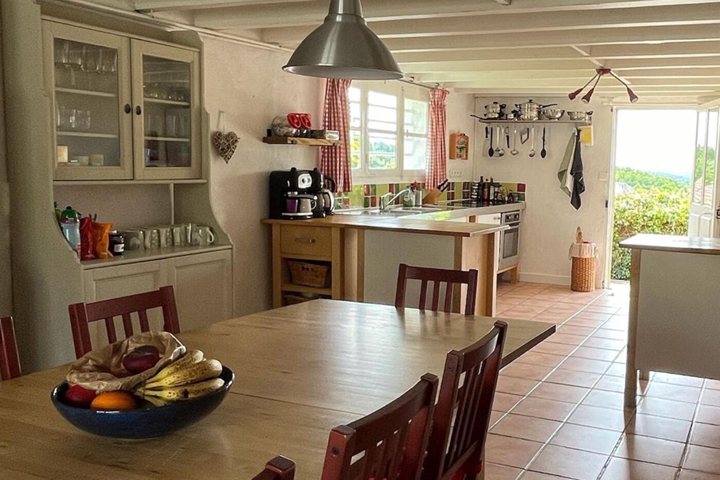A kitchen with a dining table, chairs, a coffee maker, and a window with a view.