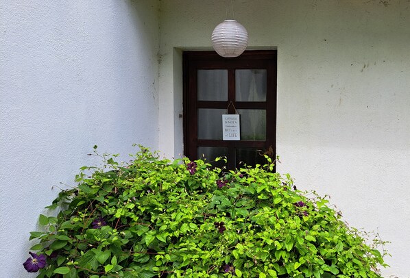 A white building with a dark wooden door and a hanging sign.