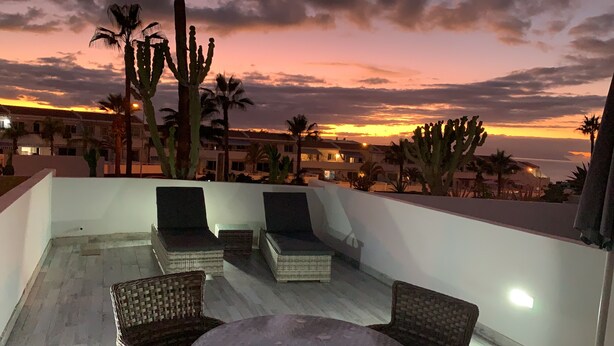 A rooftop terrace with wicker furniture, palm trees, and a sunset view. - Super nice apartment with sea view and super large terrace too  (Costa Adeje)