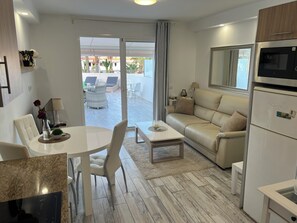 A modern living room with a dining area, a sofa, a TV, and a kitchenette. - Super nice apartment with sea view and super large terrace too  (Costa Adeje)