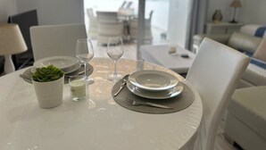 A dining table set with plates, glasses, and a small plant, with a view of a pool and lounge area in the background. - Super nice apartment with sea view and super large terrace too  (Costa Adeje)