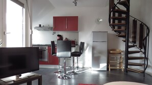 Un espace de vie compact comprenant une cuisine, un coin repas et un escalier en colimaçon.