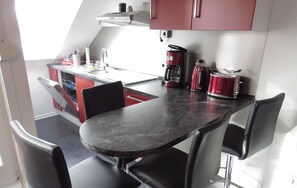 Une cuisine compacte avec un coin repas comprenant une table et des chaises, une machine à café et un grille-pain.