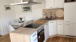 A modern kitchen with white cabinets, a wooden countertop, a built-in oven, and a stainless steel range hood.