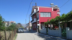Una calle con un edificio rojo, un coche aparcado y un cielo azul despejado.