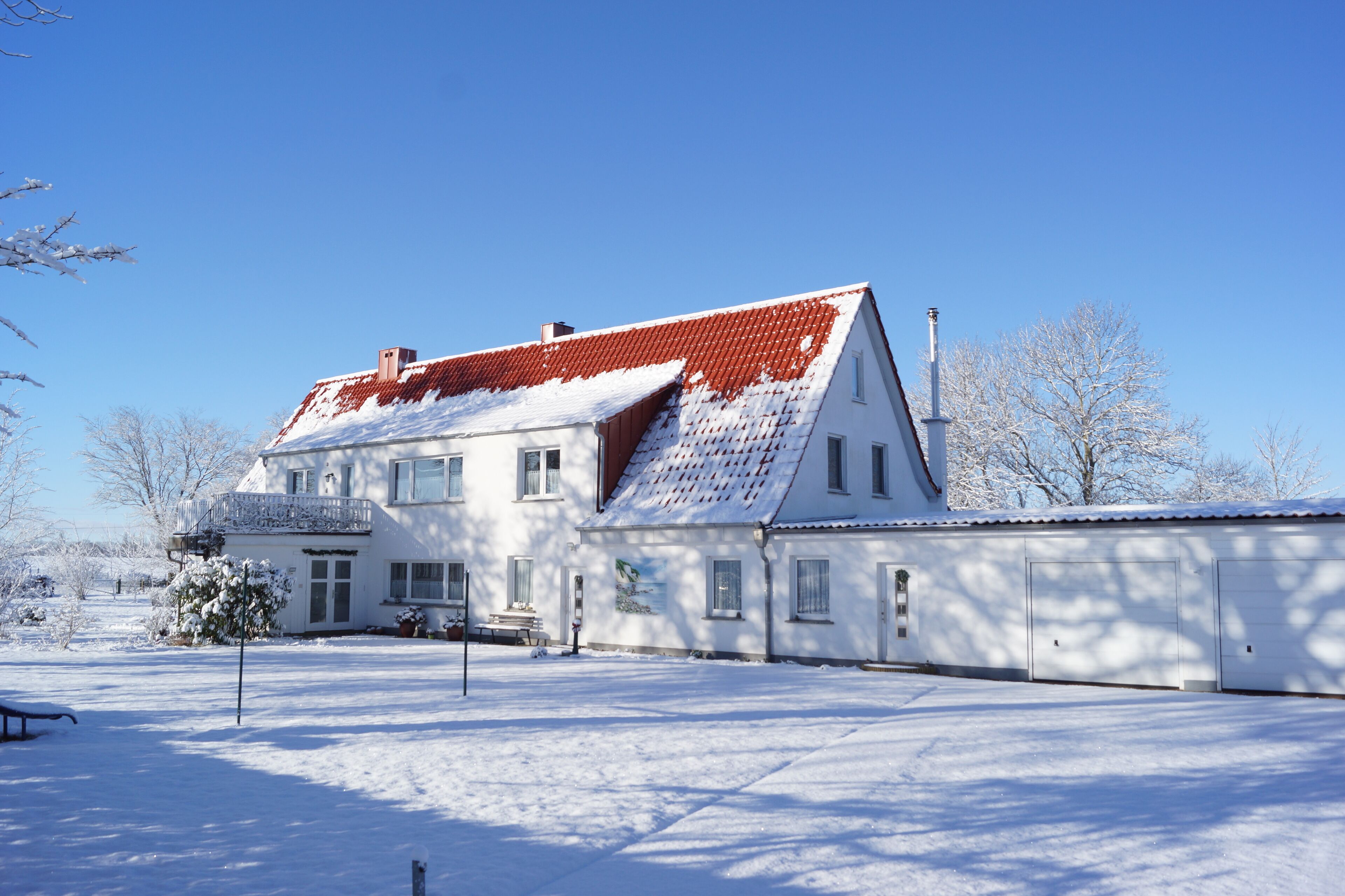 Un grand bâtiment blanc avec un toit rouge, de nombreuses fenêtres et une cour enneigée.