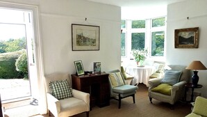 Een gezellige woonkamer met een bank, fauteuils en een salontafel. Er is een raam met uitzicht op groen.