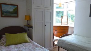 Een slaapkamer met twee bedden, een kaptafel, een spiegel en een schilderij aan de muur.