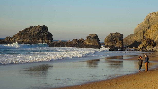 Une plage avec des formations rocheuses et des vagues.