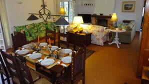 Un coin repas avec une table dressée pour quatre personnes, une cheminée et un canapé en arrière-plan.