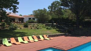 Une piscine avec une terrasse en bois et des chaises longues.