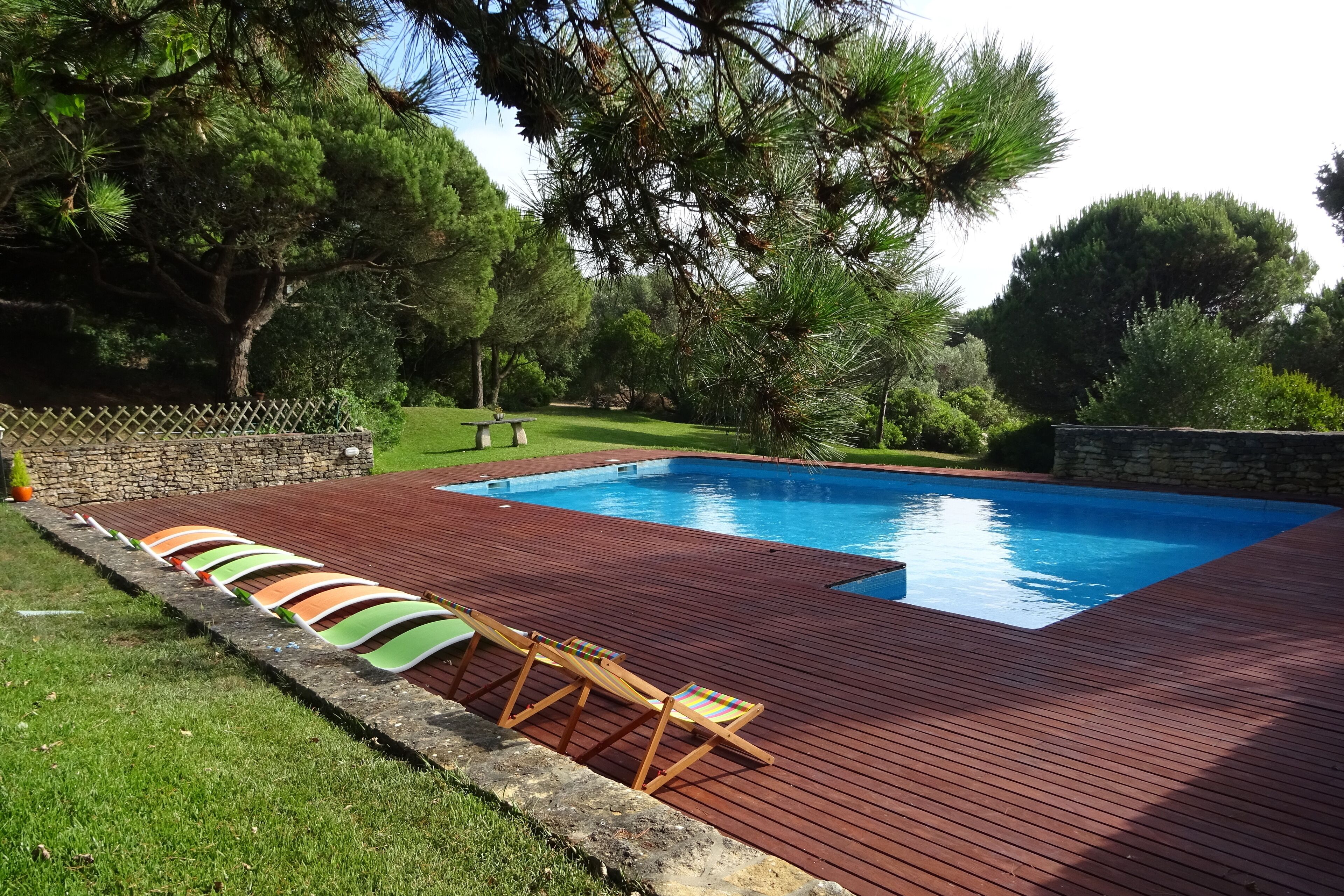 A swimming pool with a wooden deck and lounge chairs.