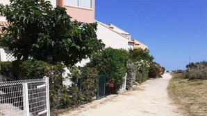 A residential street with houses, a dirt path, and a clear blue sky.