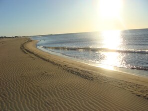Una platja amb una línia de costa corbada i ones suaus.