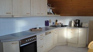 A compact kitchen with a dishwasher, oven, and a coffee maker.