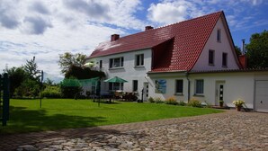 Ein zweistöckiges Haus mit rotem Ziegeldach, befestigter Auffahrt und gepflegtem Rasen.