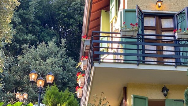 A building with a balcony, steps leading up to the entrance, and a garden with flowers. - TV119: Cute vacation home for 4 people with private pool in the countryside (Camaiore)