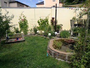 A garden with a small pond, a play area, and a wall with climbing plants. - Spacious, close to the center and family friendly apartment in Dresden! (Dresden)