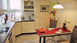 A kitchen with a dining area, including a microwave, coffee maker, and a table set for two with a red placemat. - Spacious, close to the center and family friendly apartment in Dresden! (Dresden)