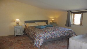 A bedroom with a bed, two bedside tables with lamps, a window with curtains, and a brick floor. - Stopover 2, in the heart of the Vendée grove (saint florent des bois)