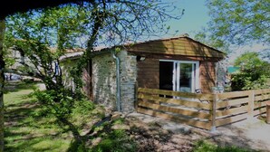 A small wooden cabin with a glass door, surrounded by greenery and a wooden fence. - Stopover 2, in the heart of the Vendée grove (saint florent des bois)