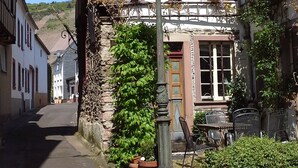 A traditional half-timbered building with a stone base, a street lamp, and potted plants. - Comfortable apartment, plus a balcony with stunning river view (Traben-Trarbach / Wolf)