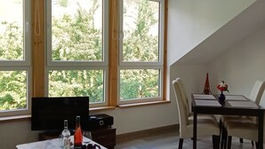 A dining area with a table and chairs, a television, and a window with a view of greenery. - Comfortable apartment, plus a balcony with stunning river view (Traben-Trarbach / Wolf)