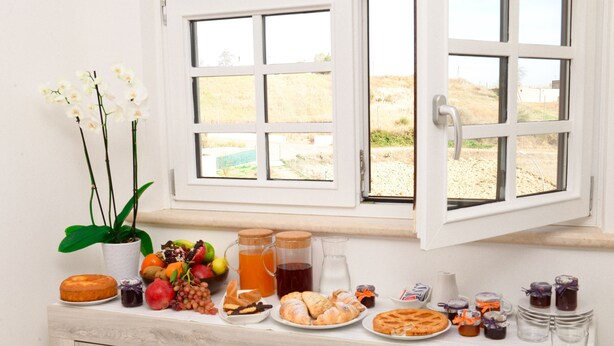 A breakfast buffet with various food items and drinks on a counter by a window. - DOMUS DAMS BED AND BREAKFAST - Room 11 (Montescaglioso)