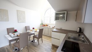 A modern kitchen with a dining area, white cabinetry, a built-in stove, and a window providing natural light. - DOMUS DAMS BED AND BREAKFAST - Room 11 (Montescaglioso)