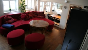 Una sala de estar moderna con un sofá rojo, otomanas, una mesa de madera y un comedor con sillas.