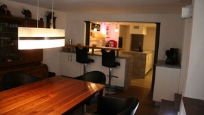 Una cocina moderna con una isla de madera, taburetes de bar y un comedor con mesa y sillas de madera.