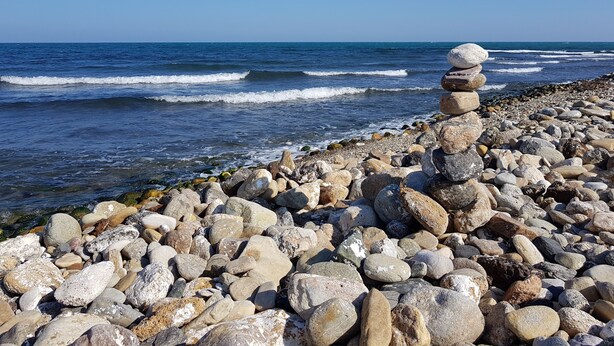 Een rotsachtige kustlijn met een stapel stenen en de oceaan op de achtergrond.