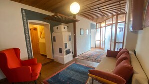 A cozy living room with a red armchair, a sofa, a patterned rug, and a unique white structure resembling a tower.