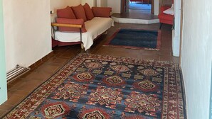 A cozy room with a wooden ceiling, a patterned rug, a sofa, and a hanging light fixture.