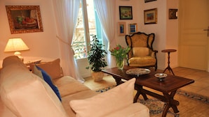 Una sala de estar con sofá, sillón y una mesa con un jarrón de flores.