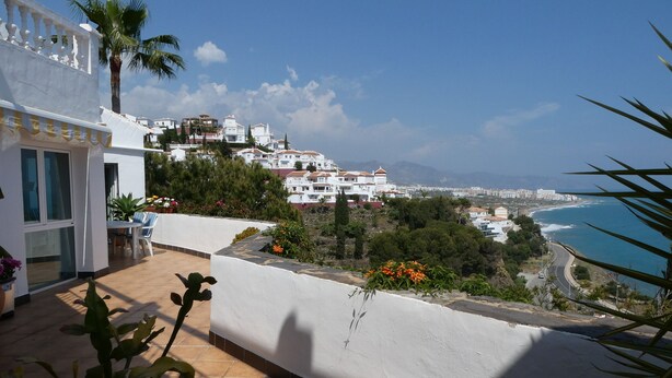 Eine Terrasse mit Blick auf Küstenhäuser und das Meer.