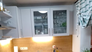 A modern kitchen with light grey cabinets, a wooden countertop, and a built-in sink. - Holidays - Holidays in the Upper Palatinate low mountain range in Bavaria in the stone forest (Reuth bei Erbendorf)