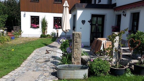 A rustic building with a stone pathway leading to a wooden table and chairs. - Holidays - Holidays in the Upper Palatinate low mountain range in Bavaria in the stone forest (Reuth bei Erbendorf)