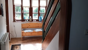 A room with a wooden bench, a radiator, a window with curtains, and a white rug. - Holidays - Holidays in the Upper Palatinate low mountain range in Bavaria in the stone forest (Reuth bei Erbendorf)