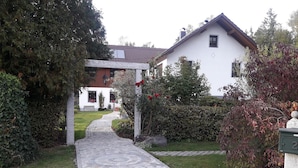 A cobblestone pathway leading to a white house with a tiled roof, surrounded by lush greenery and a hedge. - Holidays - Holidays in the Upper Palatinate low mountain range in Bavaria in the stone forest (Reuth bei Erbendorf)