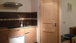 Une cuisine de taille réduite, équipée d’un lave-vaisselle, d’un évier et d’une porte en bois.