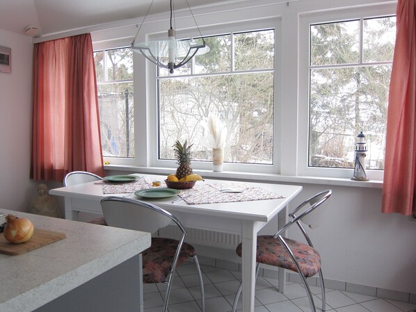 Enjoy meals in this cozy dining area with a table for two, overlooking a serene view of trees.