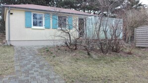 Uma casa térrea com calçada pavimentada e um pequeno jardim.