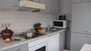 Uma cozinha compacta com armários brancos, micro-ondas, fogão e lava-louças.