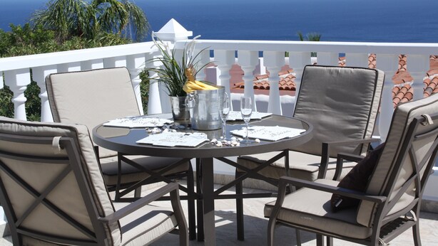 Ein runder Tisch mit Stühlen auf einem Balkon mit Blick aufs Meer.