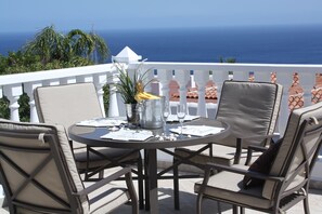 Una mesa redonda con sillas en un balcón con vistas al mar.