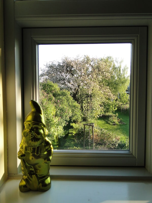 Une fenêtre donnant sur des arbres et une statue représentant une personne.