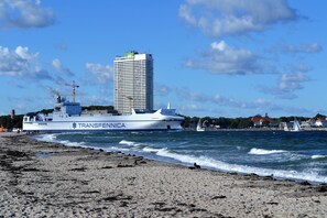 A large ship with 'Transfennica' written on its side, docked near a beach with waves.