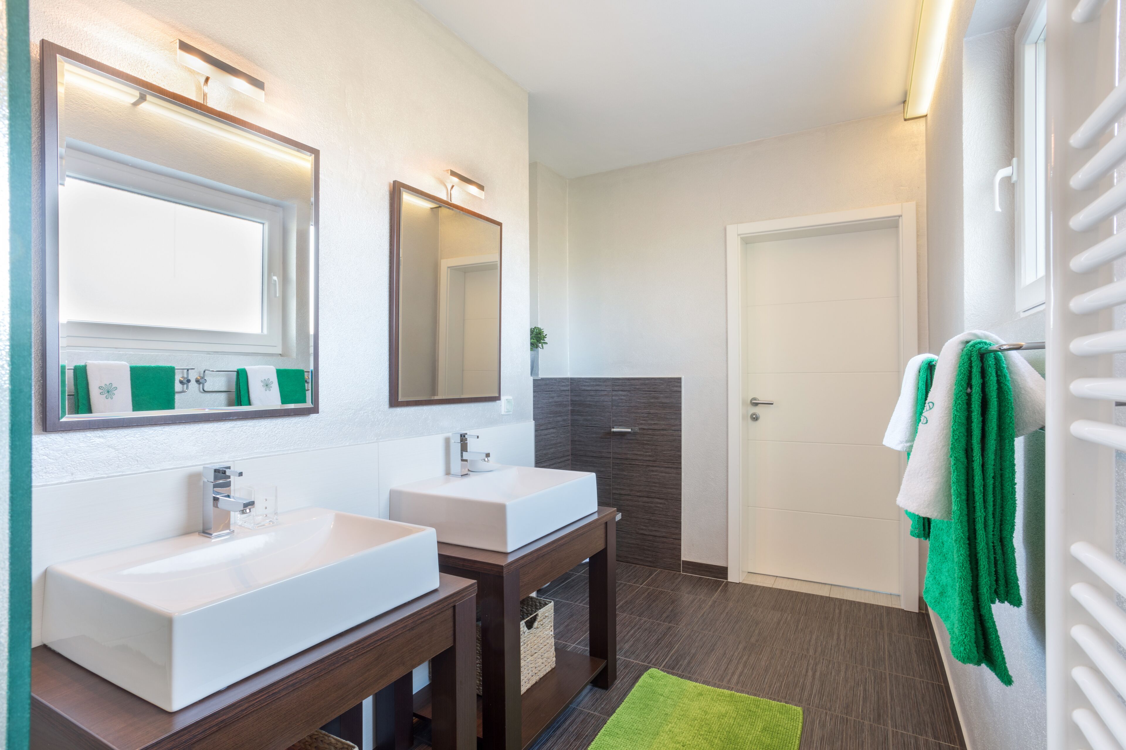 A modern bathroom with two sinks, a mirror, and a towel rack.