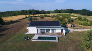 Ein modernes Haus mit Swimmingpool, umgeben von einem grünen Rasen und Bäumen.
